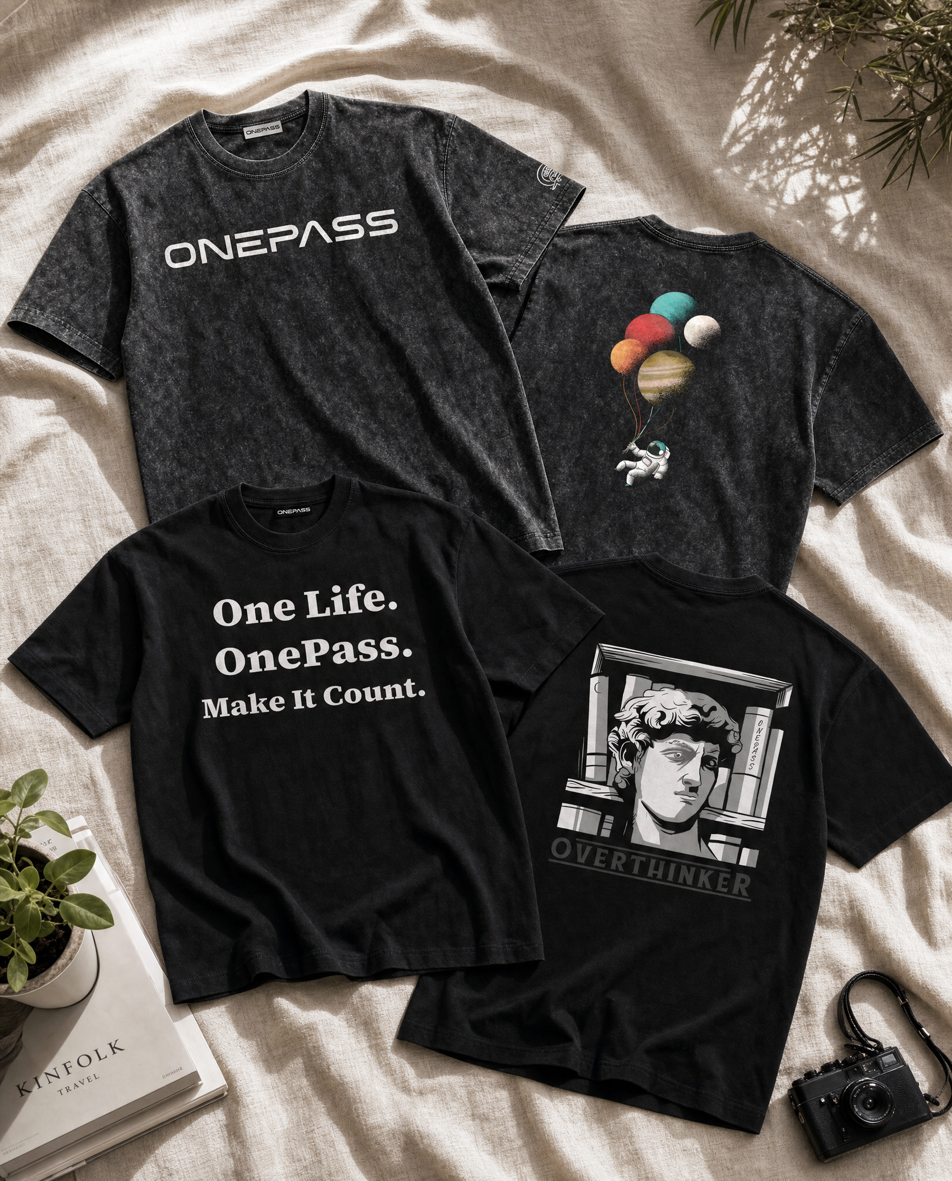 Four black t-shirts with different designs on a light fabric background.
