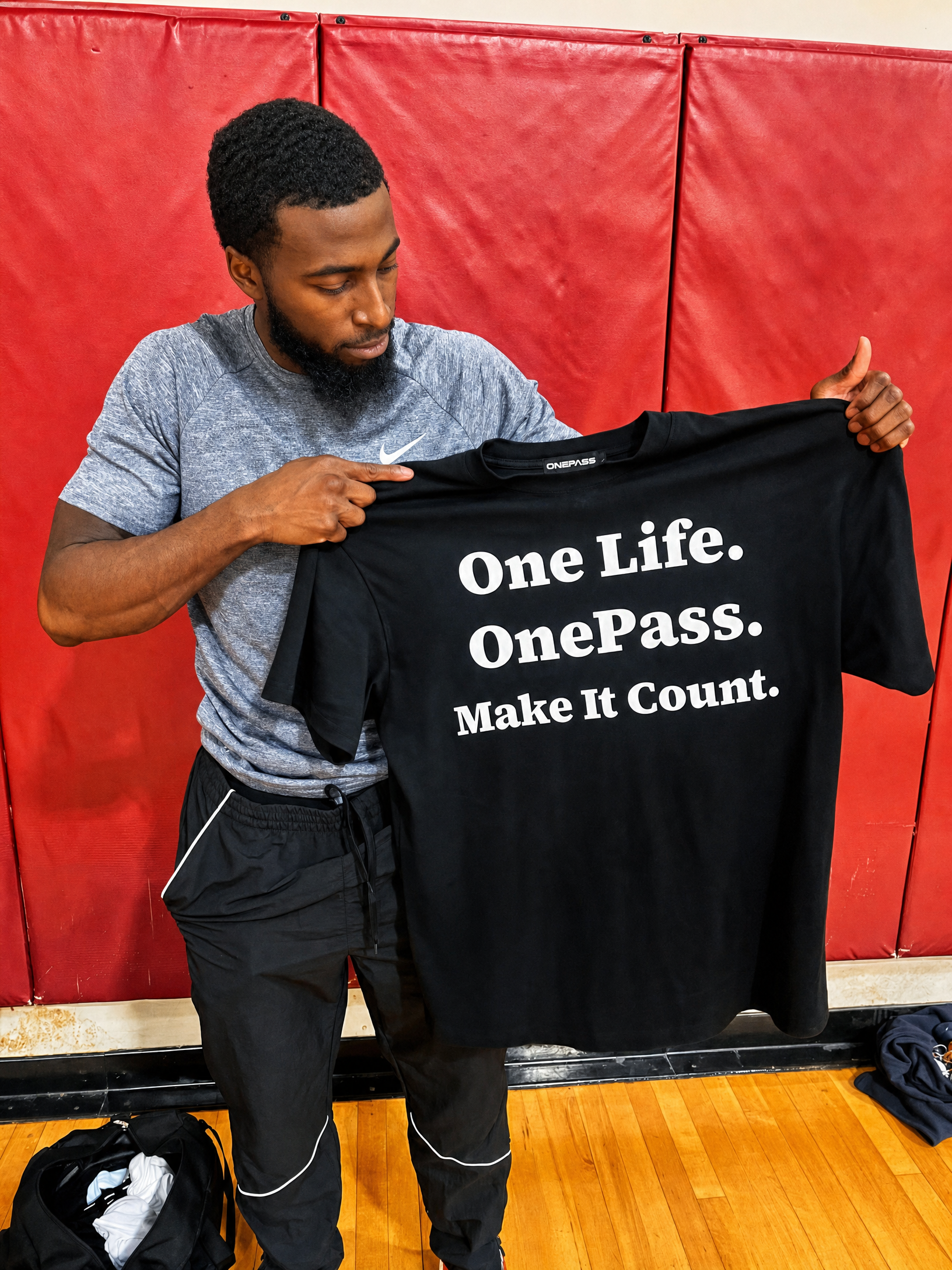OnePass founder holding the One Life OnePass Make It Count tee in a gym